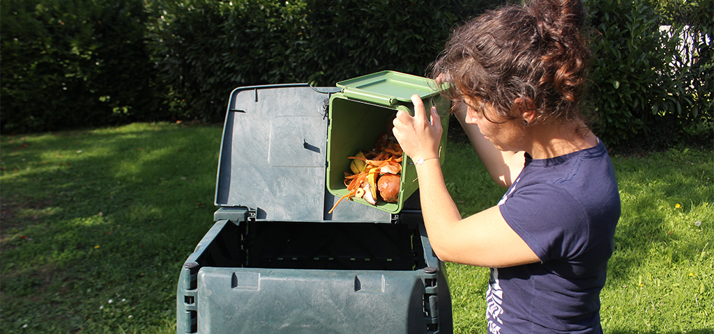 Une jeune femme verse le contenu d'un seau dans un composteur
