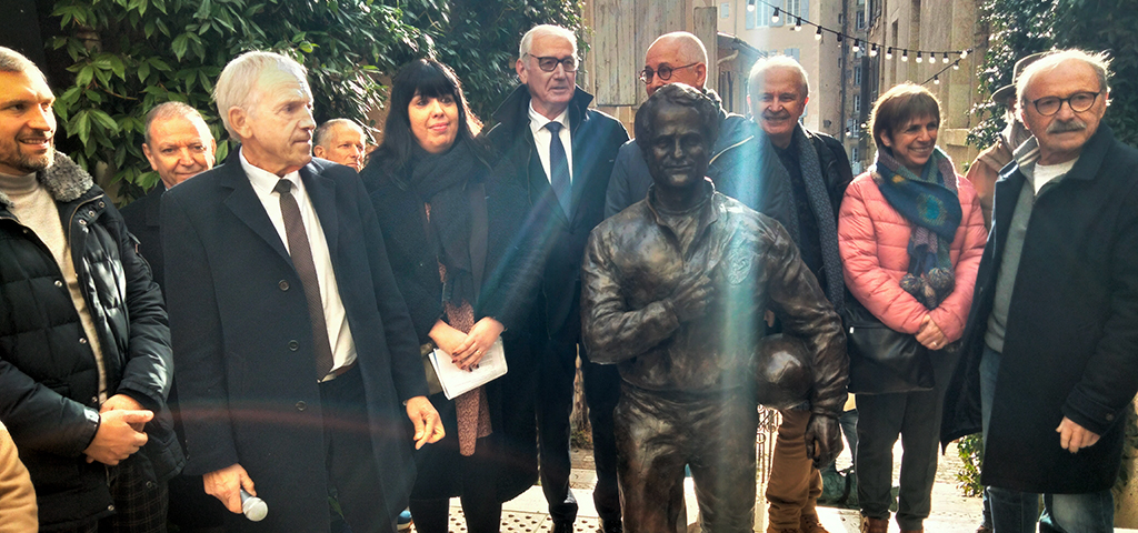 2025 - La statue de Jacques Fouroux rue Dessoles à Auch La stattue de Jacques Fouroux en bronze vue de face dans la rue Dessoles à Auch, entourée de la famille et des élus, des rais de lumière du soleil plongeant l'illumine par derrière
