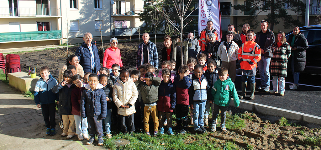 Grand Garros - les arbres de la concertation Groupe d'enfants dans le quartier du Garros à Auch, élus et agents de la ville d'Auch à l'arrière, posent devant une barre d'immeuble et les arbres fraichement plantés